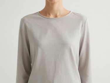 Medium shot of a model's torso, highlighting the effortless drape of a minimalist garment, soft natural daylight, clean background.