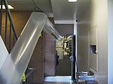 a long metal pipe in a hallway with a sink and a sink