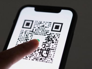 Close-up of a thumb touching a smartphone screen displaying a large QR code on a white card background — studio strobe light from above, high contrast, matte black phone edge visible at frame right, clean minimal framing