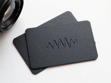 Close-up overhead flat-lay of three matte black NFC business cards fanned on a clean white surface under studio strobe light, an NFC wave embossed on the card face, minimal shadows, high contrast