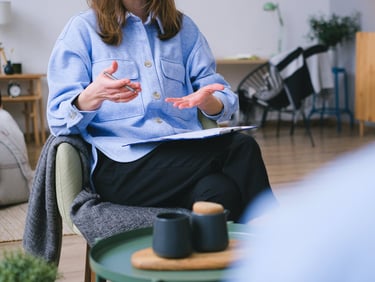 a woman in a blue shirt and black pants sitting in a chair
