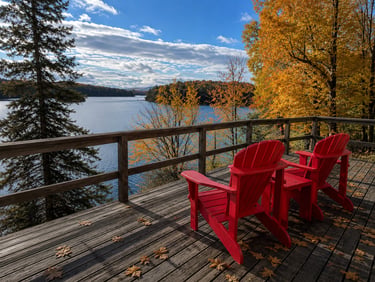 Muskoka chairs on a lakeside patio at evening.