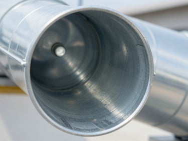 Macro close-up of a clean, bright metallic air duct interior, reflecting utility light, completely free of dust