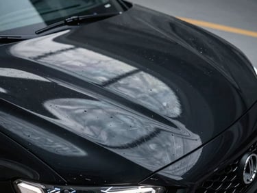 Extreme close-up of clinical overhead LED strip reflections on a wet-look black sports car hood, showing perfect paint depth and zero micro-scratches.