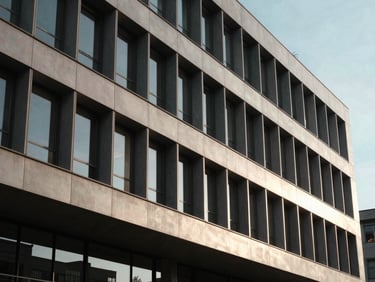A minimalist, geometric architectural shot of an elite business school campus facade with clean leading lines under dramatic afternoon window light