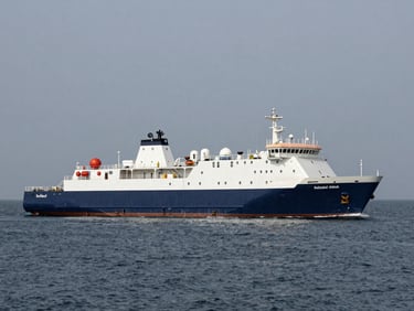 Wide shot of a clean maritime vessel operating in calm deep blue water, slate gray sky, professional engineering focus