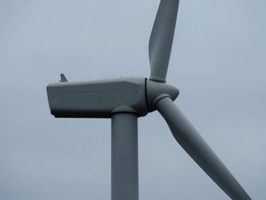 Close-up of a modern wind turbine base with clean architectural lines against a cool overcast sky