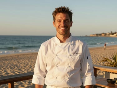 Portrait of a smiling chef in a clean white uniform on a sunlit beach deck, warm golden-hour light