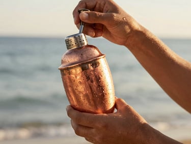 Close-up of hands shaking a tropical cocktail in a copper shaker, sweating in the heat, warm light