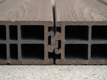 Macro architectural cross-section of interlocking WPC decking panels, showing internal hollow-core structure, crisp studio lighting, warm stone tones, sharp focus.