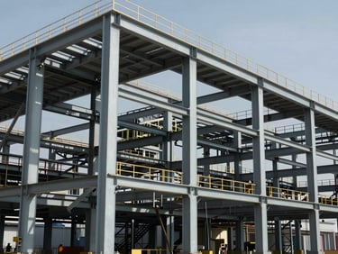 Industrial plant structural steel skeleton, heavy columns and rafters, high contrast daylight.