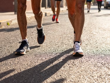 Vibrant athletic photography of runners' shoes on asphalt during bright early morning sunlight on Querétaro streets, dynamic low-angle action shot