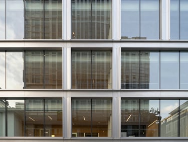 Symmetric architectural shot of a modern corporate office building facade with steel and reflective glass panels