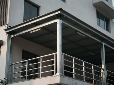Fabricated steel canopy and railing installed on a building exterior, Tangerang, sharp welded edges, tungsten construction-site lighting, real facade context