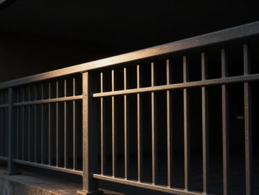 Architectural steel balustrade with clean geometric lines, dramatic side-lighting casting long shadows, dark charcoal tones.