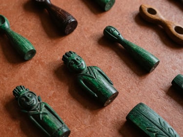 Close-up of hand-carved Paraguayan wooden objects on a textured terracotta surface under soft ambient indoor light, rich shadows