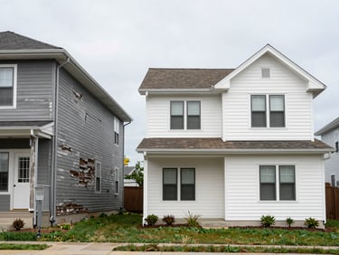 Split-frame wide exterior shot: left half shows a home with visibly failing dark siding and sagging gutters under flat overcast light; right half shows the same elevation fully restored with clean new siding and aligned gutters, shot straight-on at midday, no people, no styling