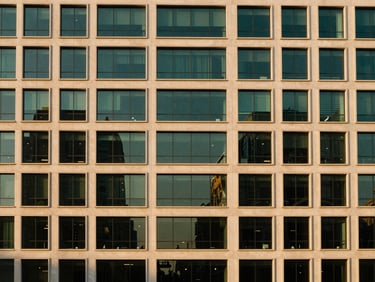 Modern commercial building facade with glass reflections, architectural symmetry, elegant lighting