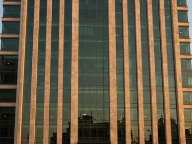 Modern commercial glass skyscraper facade in Islamabad at dusk, warm golden light reflecting off premium materials, clean symmetrical composition, 35mm