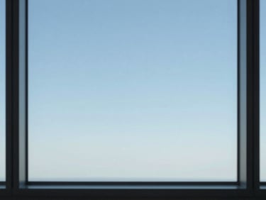 Minimalist high-altitude horizon line looking out from a high-rise window, crisp daylight, expansive sky
