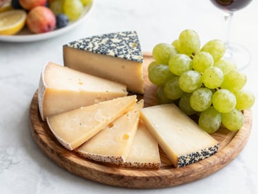 Overhead shot of an elegant savory station with cheeses and grapes on a wooden board.