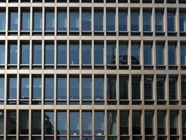 Architectural shot of a modern office building facade, clean lines, geometric symmetry, bright natural daylight, deep navy tones, 35mm