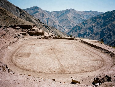 Low-angle wide shot of a dirt football pitch carved into a steep Andean mountain ridge in Peru, harsh midday sun, dry clay earth, peaks in background, 35mm film.