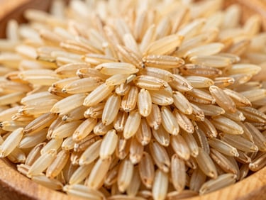 Close-up of golden Basmati rice grains in a wooden bowl, bright natural daylight, rich organic tones, high detail, 35mm