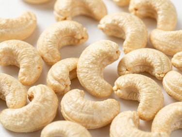 Close-up of whole, pale cashews, perfectly roasted, in a clean modern setting with bright light