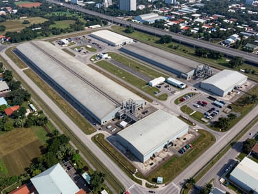 Aerial diagonal view of a large industrial land parcel near Iskandar Malaysia zone, boundary clearly delineated, highway visible in background, daylight