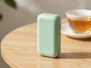 A compact, elegant portable locator device resting on a wooden table next to a cup of tea, soft morning light, warm editorial style.