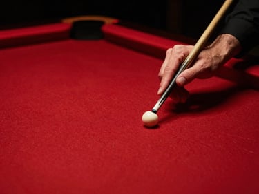 Close-up of hands chalking a pool cue over tournament-grade red felt, moody low-light, dramatic red neon accents, high-contrast