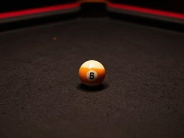Close-up of billiard balls on premium dark felt under a single overhead warm light