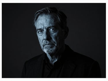 Dramatic high-contrast studio portrait of a founder in dark clothing, sharp rim lighting, deep charcoal background, 35mm
