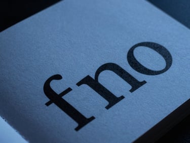 Extreme close-up of a minimalist printed brand book with sharp black typography on heavy textured paper, cool studio lighting
