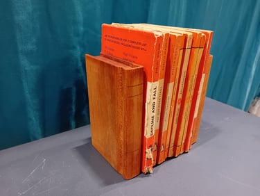 Pail of book-shaped wooden bookends around a set of orange books