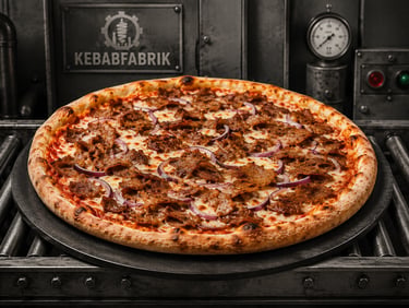 Freshly baked kebab pizza with sliced meat and red onions on an industrial conveyor belt.