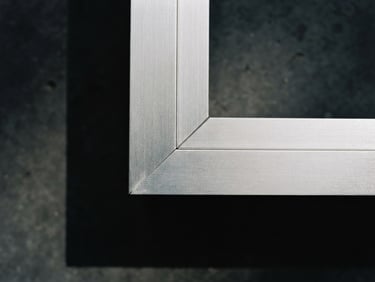 Close-up of a perfectly mitered aluminum joint under bright workshop lighting, sharp architectural shadows, minimalist composition, 35mm lens