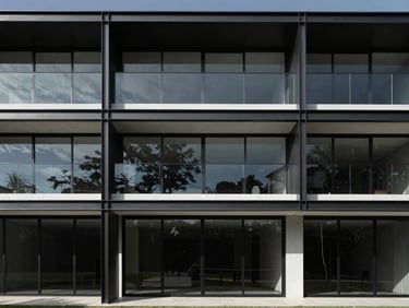 Wide shot of a modern residential facade with expansive glass panels and dark aluminum frames, seamlessly integrating indoor and outdoor spaces, sharp architectural shadows, Tangará da Serra landscape in background, architectural photography, high-contrast, minimalist composition, 35mm lens.