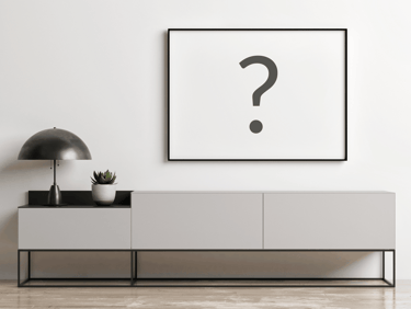 Modern minimalist interior with a black picture frame mockup over a grey sideboard cabinet.