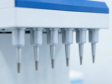 Macro close-up of automated laboratory liquid handling instrumentation, sterile clinical setting, high-key white background, sharp focus, 35mm