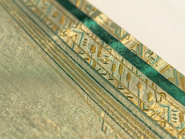 Close-up of intricate gold and emerald green silk textile weave, detailing the delicate warp and weft threads, soft natural daylight
