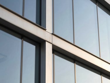 Close-up of modern structural glass curtain wall joints, clean aluminum profiles, crisp architectural lines, daylight.