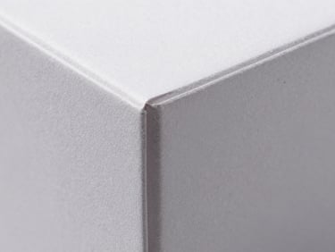 Macro shot of a perfectly folded SBS box corner, showing crisp edges and a subtle matte finish, sharp studio lighting, deep shadows.