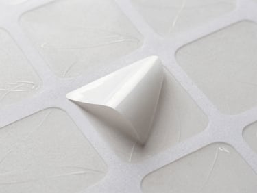 Overhead view of a sheet of custom-shaped, laser-cut vinyl stickers, some peeled away, showing the intricate cut lines and glossy finish, studio lighting.