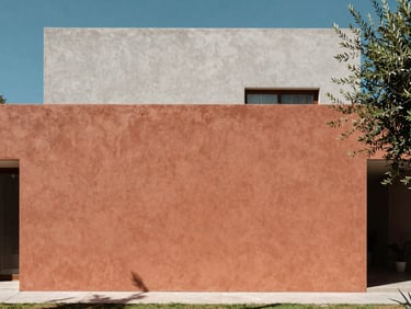 Warm terracotta facade of a modern minimalist villa in San Miguel de Allende, clean lines, olive tree shadow, bright daylight