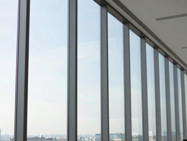 Modern office space with floor-to-ceiling windows, subtle heat reduction film applied, bright natural daylight, clean glass reflections, 35mm lens