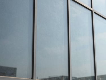 Close-up of a glass pane with a barely visible security film, showing slight reinforcement texture, cool tones, 35mm lens
