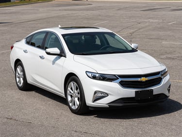 Three-quarter front view of a clean 2020 Chevrolet Malibu in pearl white on a bright outdoor lot under even daylight, neutral asphalt background, no people