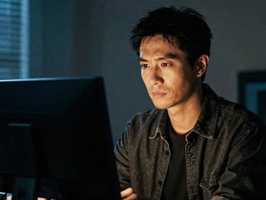High-contrast character portrait of a male designer holding a monitor, blue and amber lighting, gritty cinematic texture.